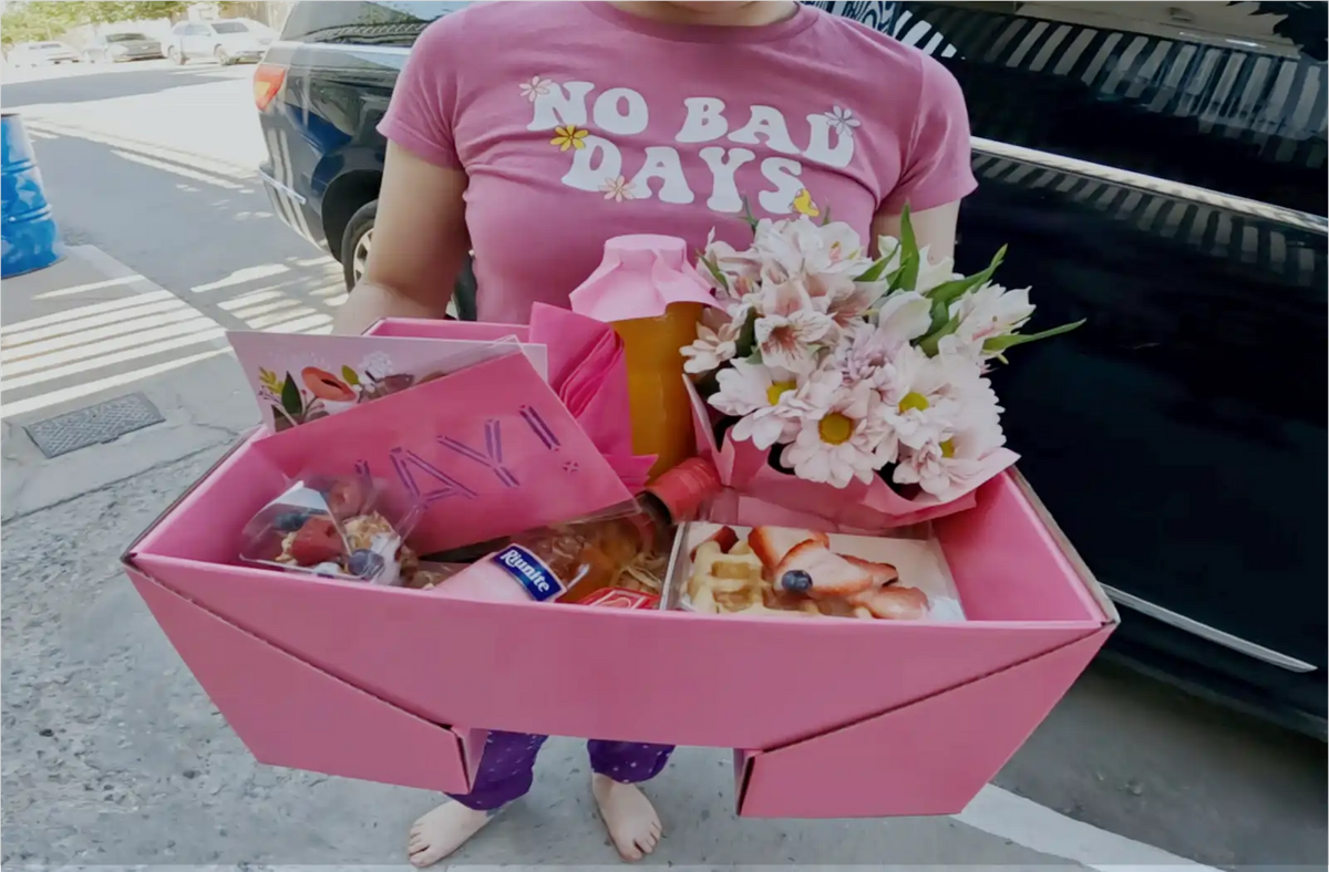 Persona descalza con desayuno sorpresa en la mano, lo ha recibido en cuidad juarez por lemons regalos. su playera dice no bad days y es la prueba de entrega de lemons
